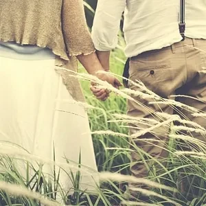 Man in Suspenders Holding Hands with Woman in Grassy Knoll - FarmersOnly