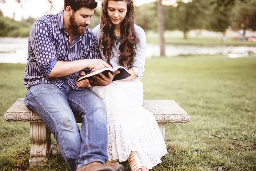 Couple sitting on a bench reading the Bible