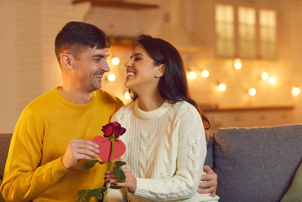 Man and woman smiling with a rose on the couch